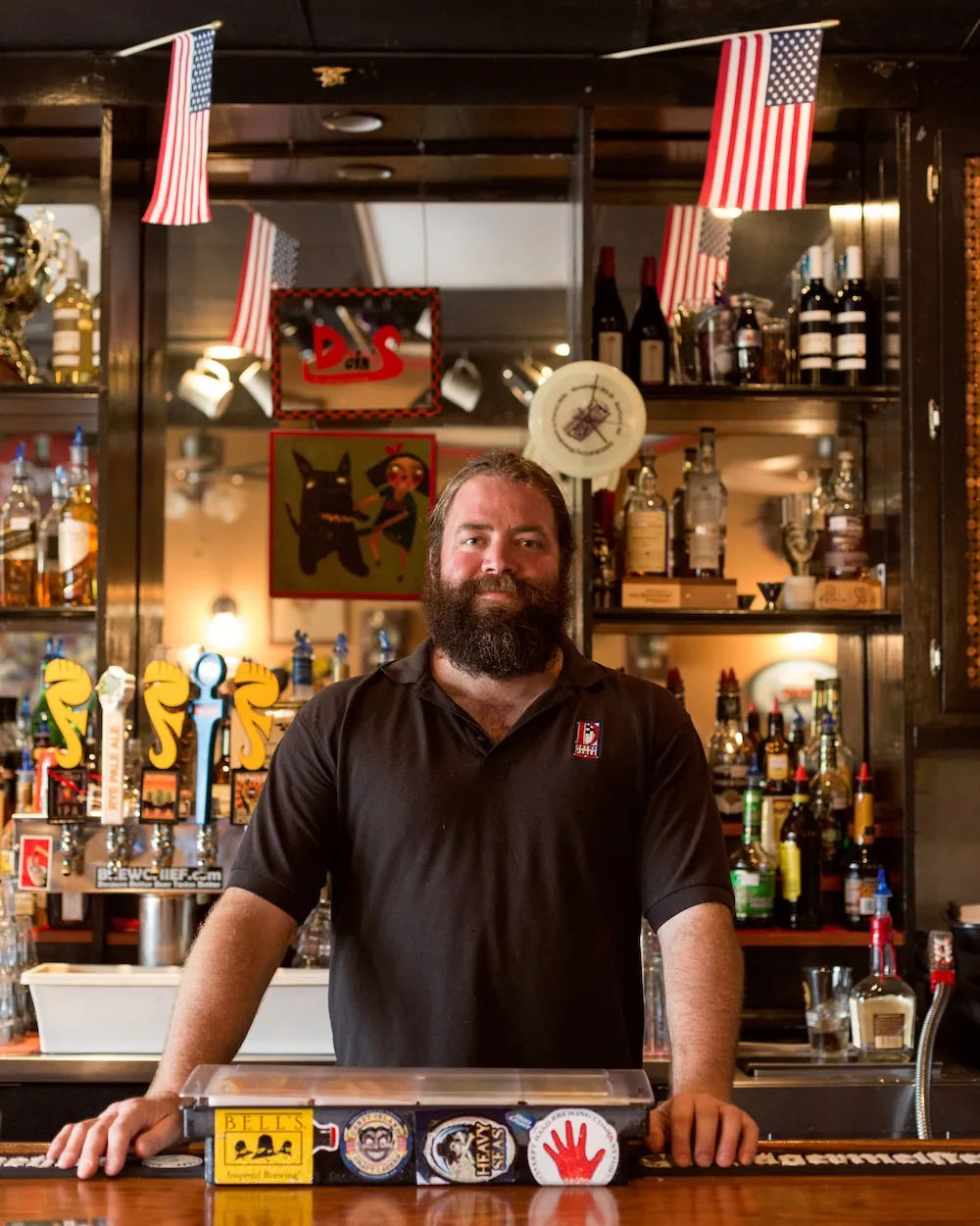 Dain Phelan standing behind his bar, smiling proudly. Credit: Indy Weekly